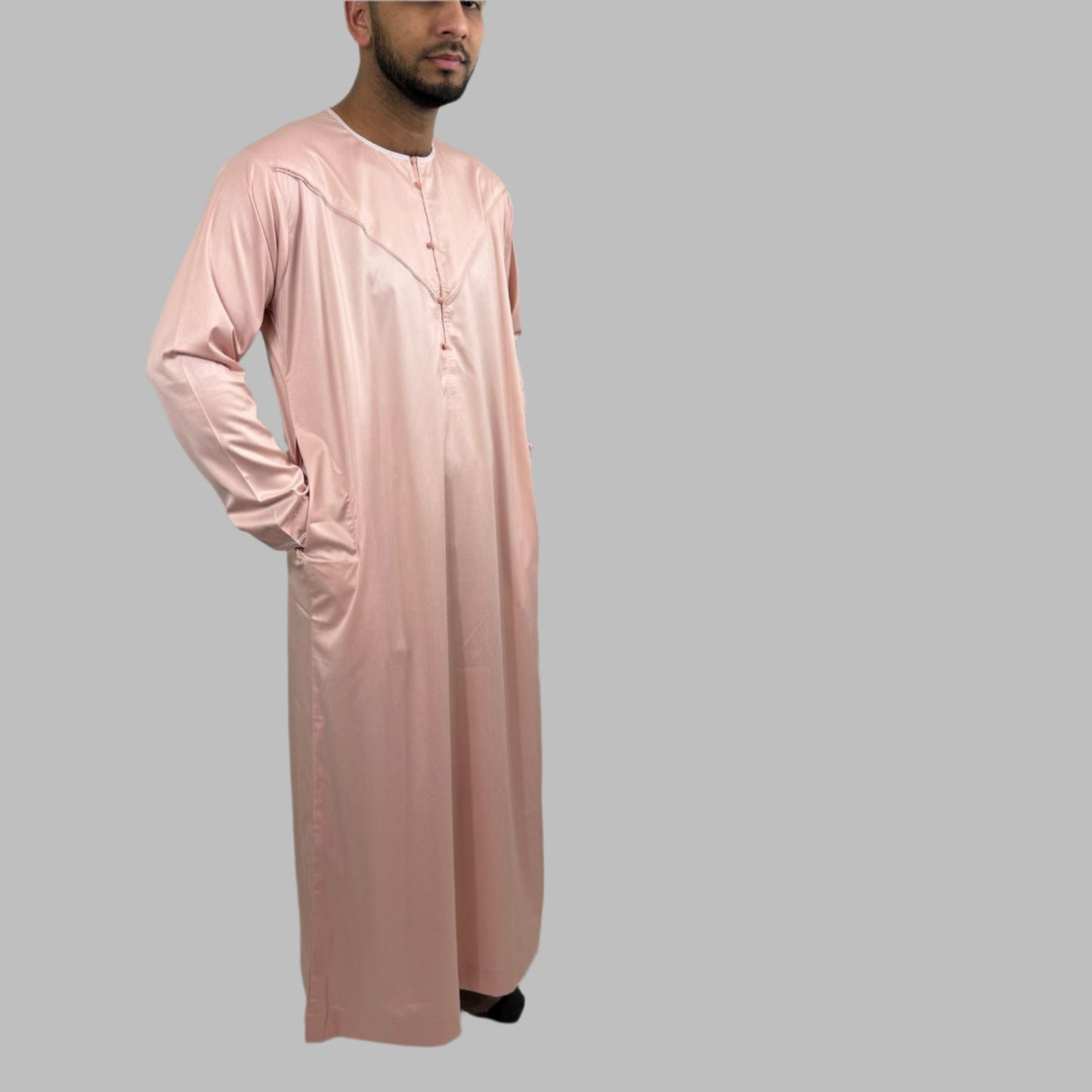 Traditional Emirati thobe in blush pink satin with intricate chest embroidery and piping details.