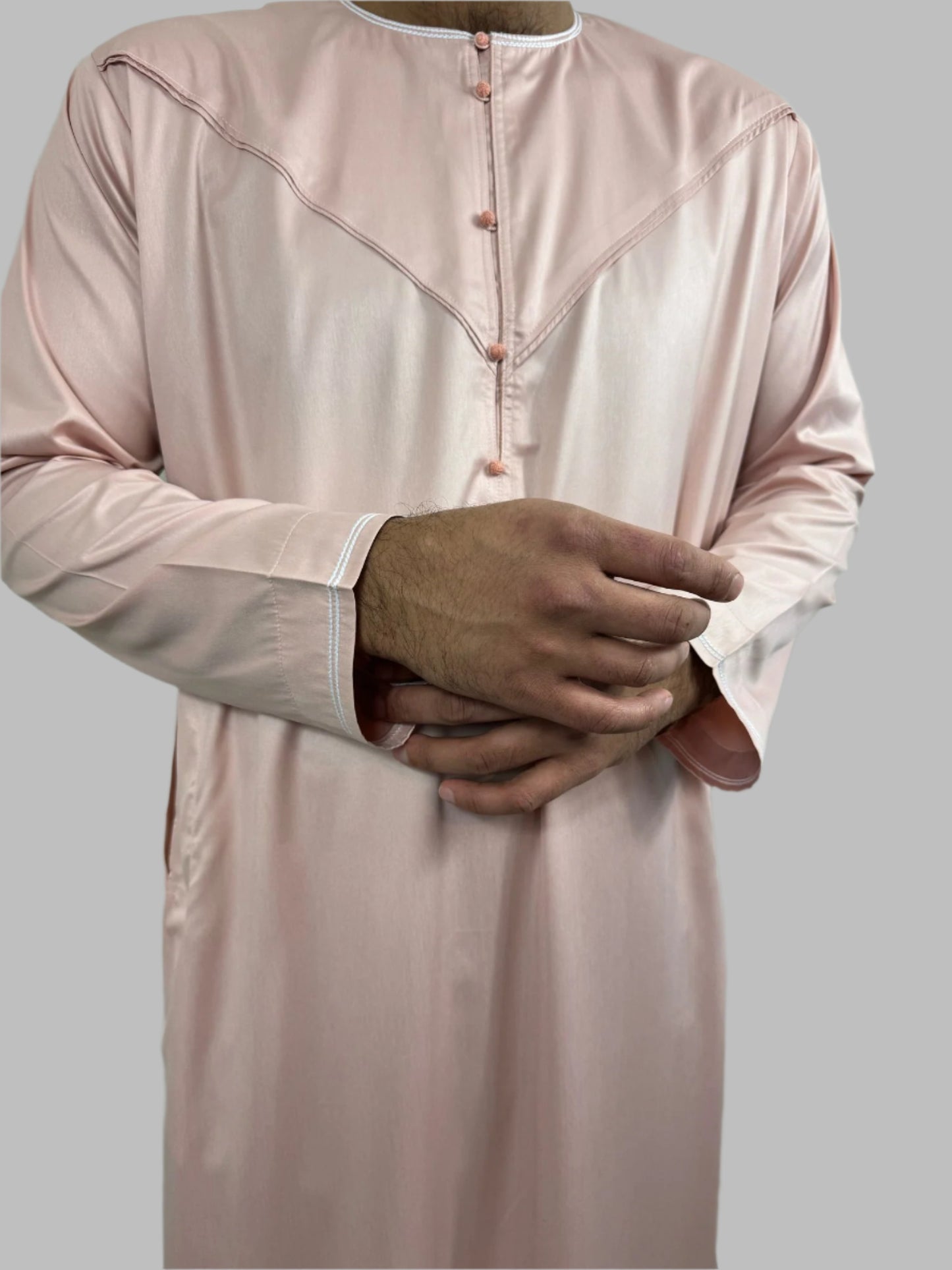 Detailed close-up of Al-Majd Thobe’s sleeves with white piping on cuffs and rounfd cloth button
