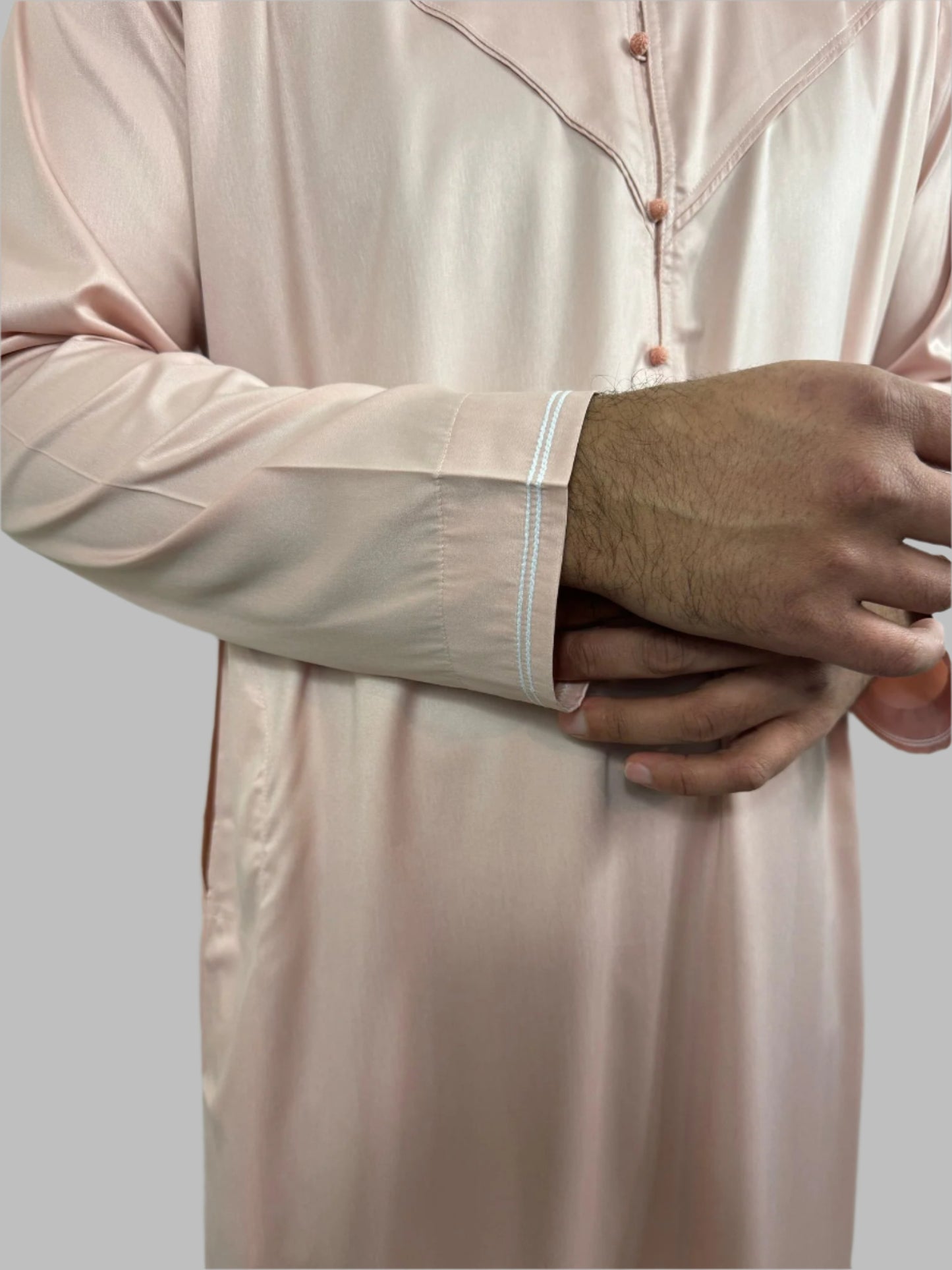 Detailed close-up of Al-Majd Thobe’s sleeves with white piping on cuffs.