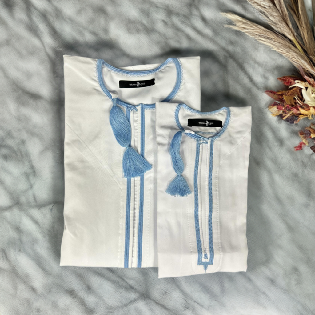 "Father and son matching Mikhael white thobes withsky blue accents, elegantly folded, showcasing traditional style and coordinated design."