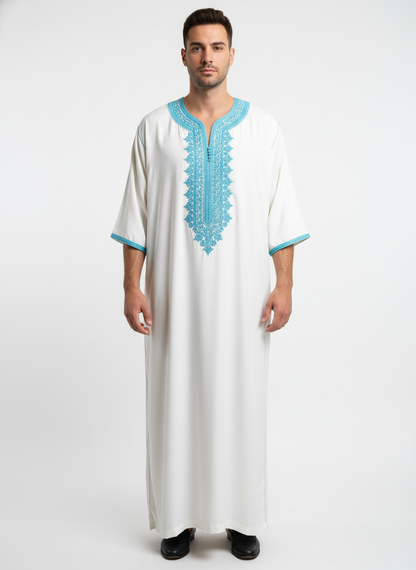 White Moroccan Gandoura with detailedlight blue embroidery and centralbuttons showcasing refined craftsmanship.”