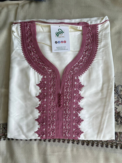  “White Moroccan Gandoura with detailed pink embroidery and central buttons , showcasing refined craftsmanship.”