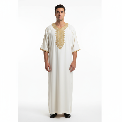 “White Moroccan Gandoura with intricate gold embroidery and tassel detail, folded neatly with branded tag.”