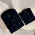 Two navy blue shirts with gold buttons on a white woven surface